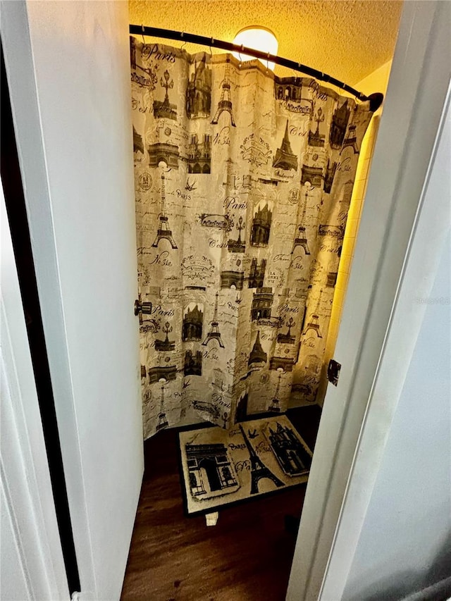 bathroom with a textured ceiling, walk in shower, and hardwood / wood-style flooring