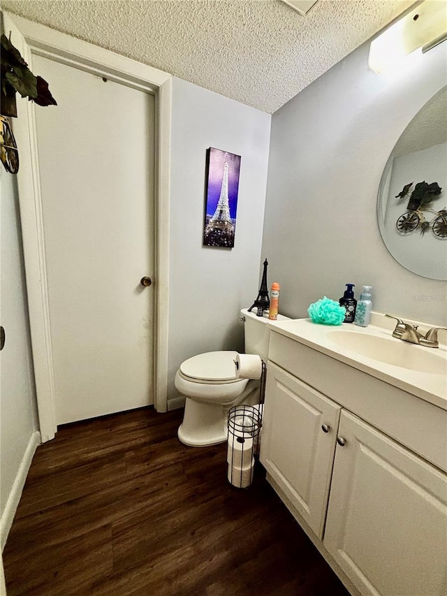 bathroom featuring hardwood / wood-style floors, a textured ceiling, vanity, and toilet