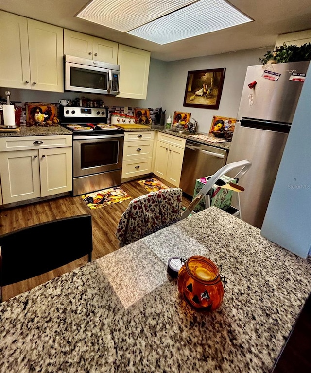 kitchen with stainless steel appliances, dark hardwood / wood-style floors, and stone counters