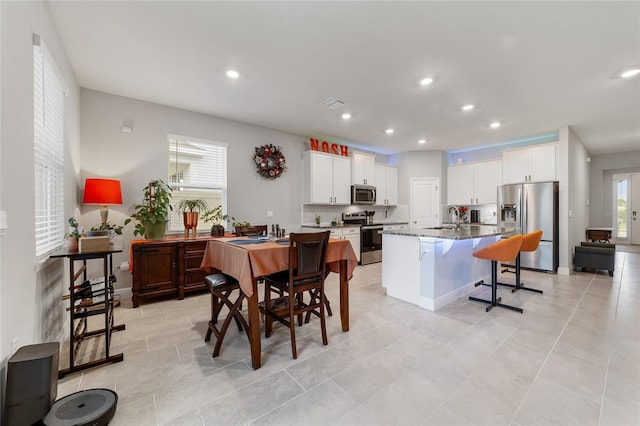 kitchen featuring dark stone counters, sink, an island with sink, white cabinetry, and stainless steel appliances