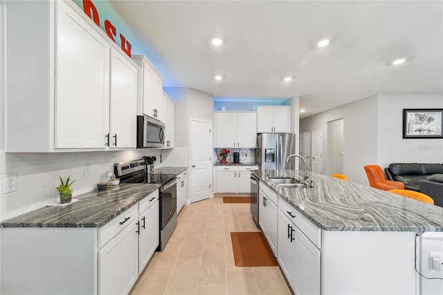 kitchen with an island with sink, appliances with stainless steel finishes, sink, and white cabinetry