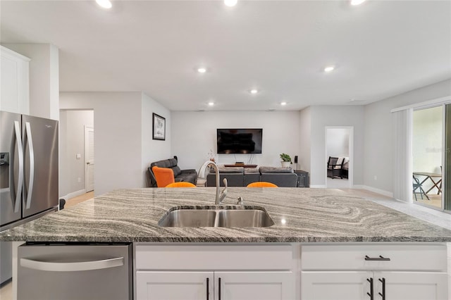 kitchen with appliances with stainless steel finishes, stone counters, sink, and white cabinetry