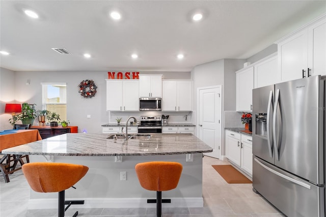 kitchen featuring a kitchen island with sink, sink, stainless steel appliances, and white cabinets