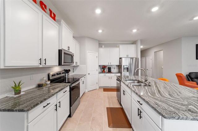 kitchen with an island with sink, stainless steel appliances, sink, and white cabinetry