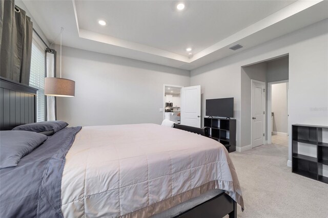 bedroom with a tray ceiling and light carpet