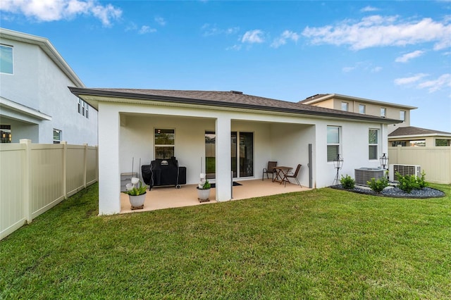 back of property with a lawn, a patio, and central AC unit