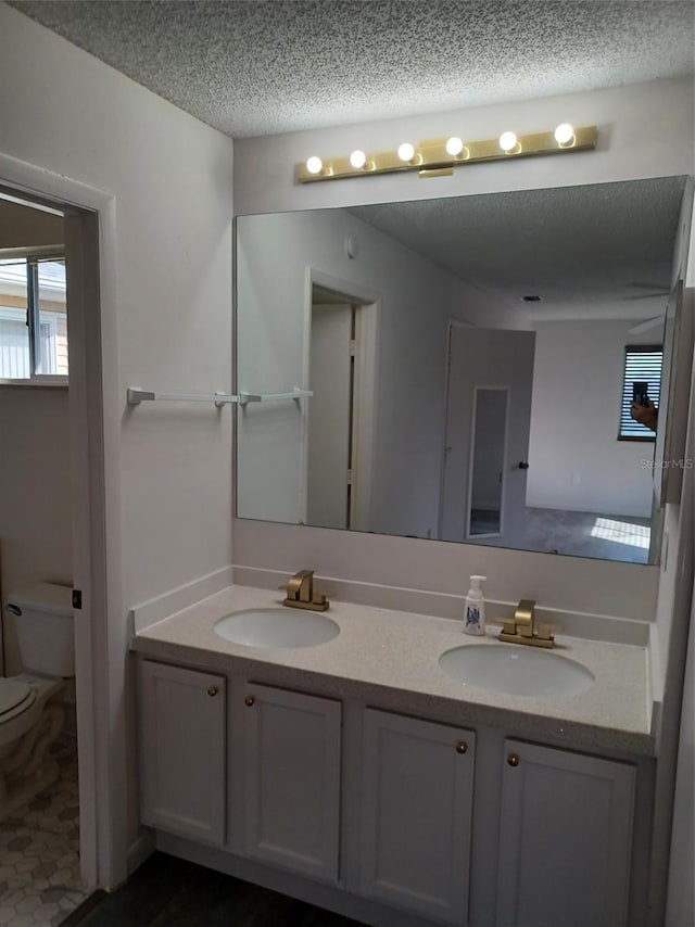 bathroom with vanity, toilet, and a textured ceiling