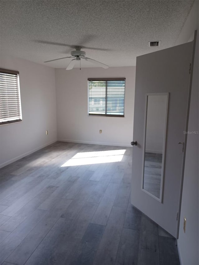 empty room featuring a textured ceiling, wood-type flooring, and ceiling fan