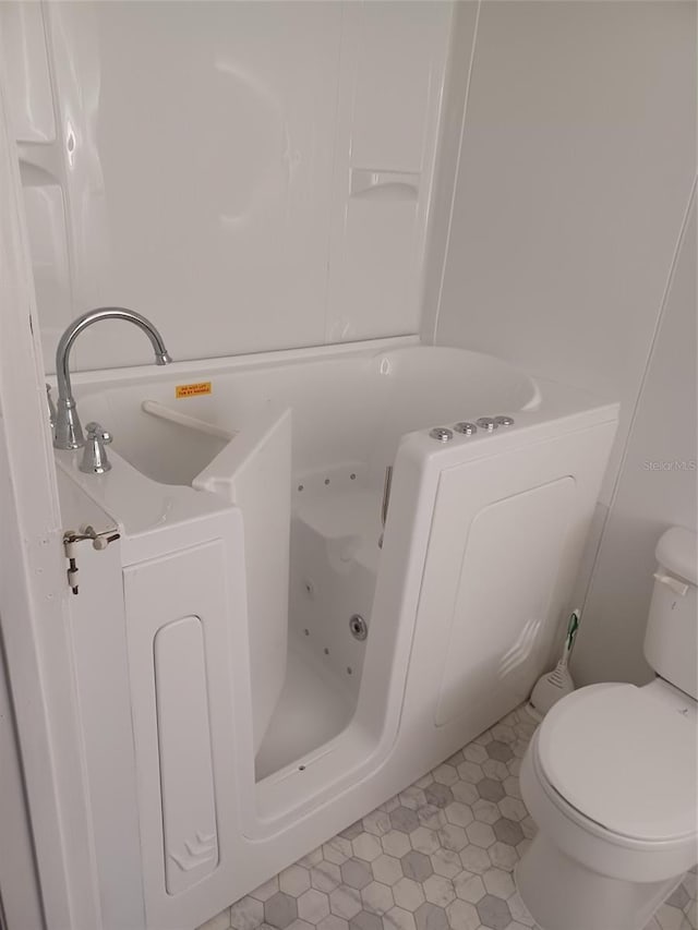 bathroom with a bathtub, toilet, and tile patterned floors