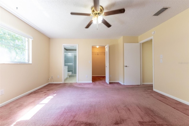 unfurnished bedroom featuring ceiling fan, connected bathroom, light carpet, and a spacious closet