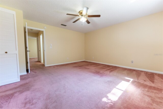 empty room with a textured ceiling, ceiling fan, and light colored carpet