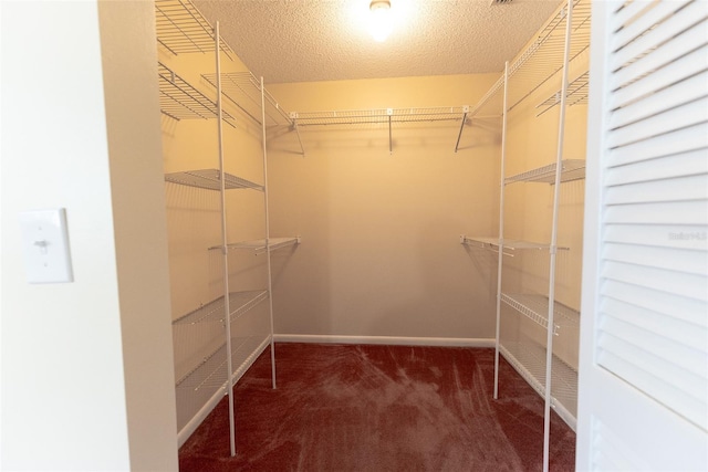 walk in closet featuring dark colored carpet