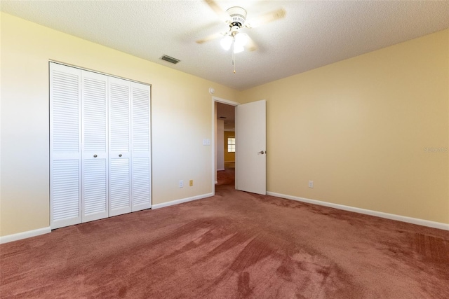 unfurnished bedroom with a textured ceiling, ceiling fan, a closet, and carpet flooring