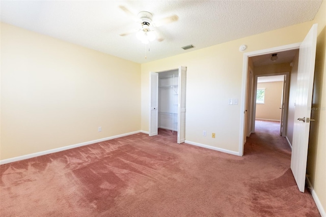 unfurnished bedroom with a textured ceiling, ceiling fan, a closet, and carpet flooring