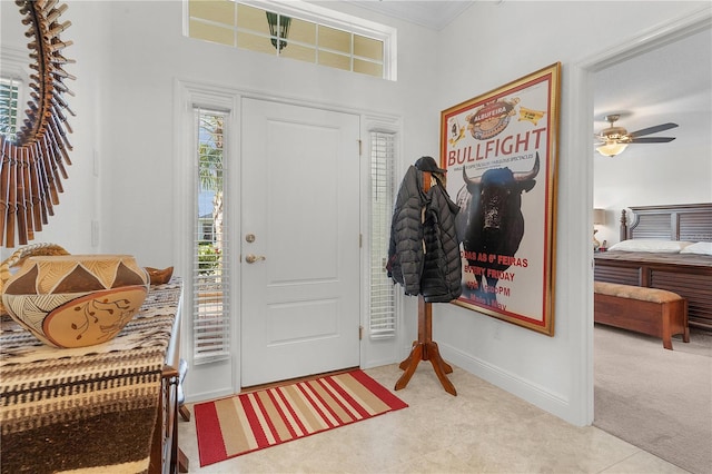 carpeted foyer entrance with crown molding and ceiling fan