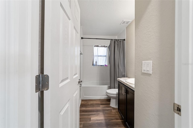 full bathroom with a textured ceiling, shower / tub combo, hardwood / wood-style floors, vanity, and toilet