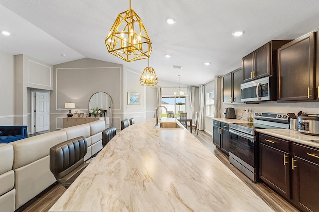 kitchen with appliances with stainless steel finishes, hanging light fixtures, lofted ceiling, hardwood / wood-style flooring, and sink