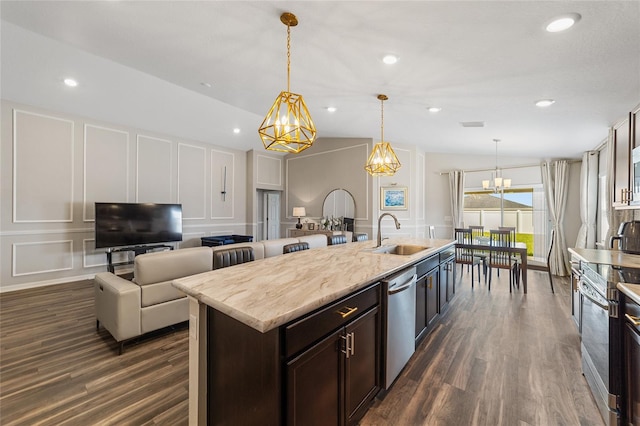 kitchen featuring lofted ceiling, sink, dark brown cabinets, decorative light fixtures, and appliances with stainless steel finishes