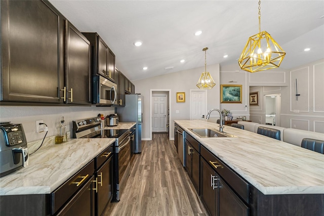 kitchen featuring appliances with stainless steel finishes, vaulted ceiling, dark wood-type flooring, pendant lighting, and sink