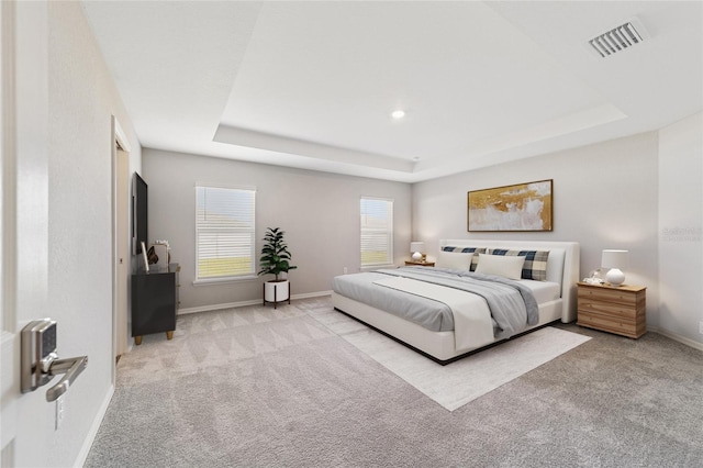 bedroom with a tray ceiling and light colored carpet