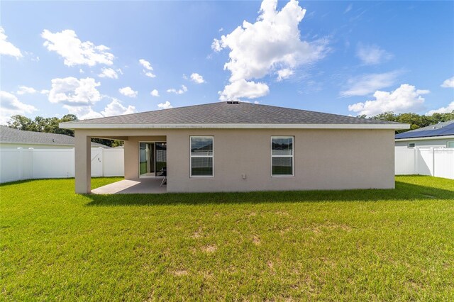 rear view of property featuring a lawn and a patio area