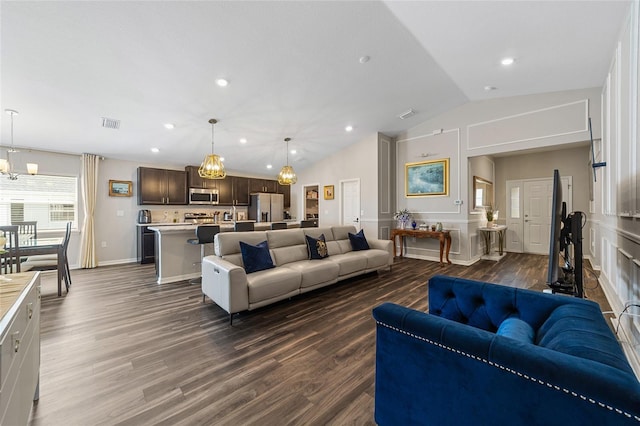 living room featuring an inviting chandelier, vaulted ceiling, and dark hardwood / wood-style floors