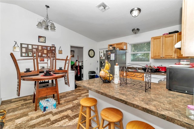 kitchen featuring fridge with ice dispenser, dark wood-type flooring, a chandelier, a kitchen breakfast bar, and vaulted ceiling