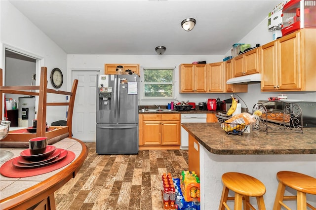 kitchen with sink, stainless steel refrigerator with ice dispenser, dishwasher, a breakfast bar area, and dark hardwood / wood-style flooring