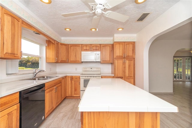 kitchen featuring ceiling fan, white appliances, a kitchen island, a textured ceiling, and light hardwood / wood-style flooring