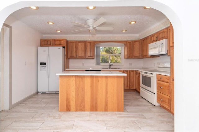 kitchen with white appliances, a kitchen island, sink, and a textured ceiling