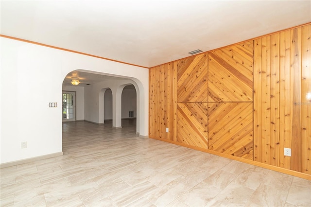 empty room featuring wood walls and ornamental molding