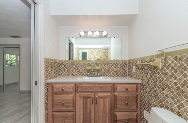 bathroom with vanity, tile walls, and toilet