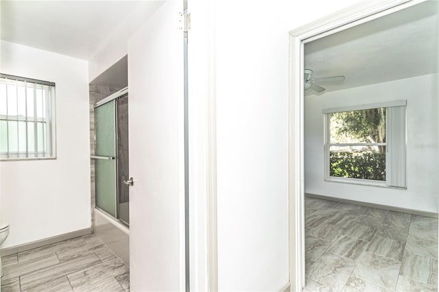 bathroom featuring ceiling fan, enclosed tub / shower combo, and toilet