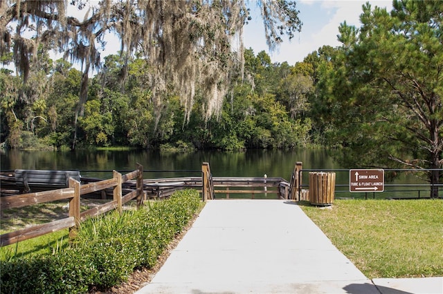 surrounding community with a water view and a lawn