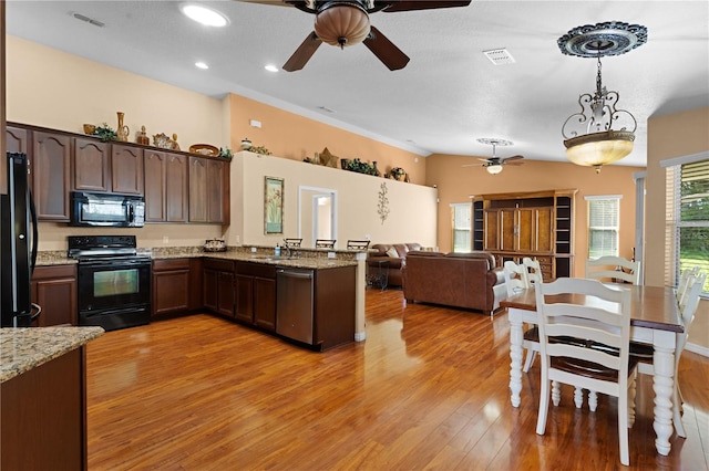 kitchen with light stone countertops, pendant lighting, light wood-type flooring, black appliances, and dark brown cabinetry