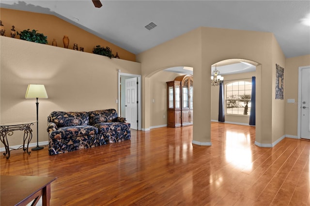 living room featuring ceiling fan with notable chandelier, light wood-type flooring, and lofted ceiling