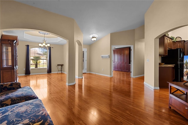 living room featuring light hardwood / wood-style floors, a tray ceiling, and a notable chandelier