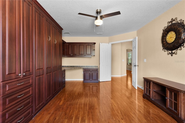 kitchen featuring light stone countertops, ceiling fan, dark wood-type flooring, and a textured ceiling