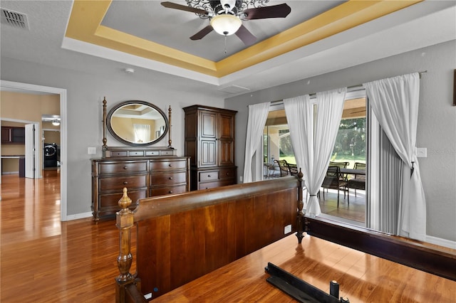 interior space featuring washer / dryer, a tray ceiling, ceiling fan, and hardwood / wood-style flooring