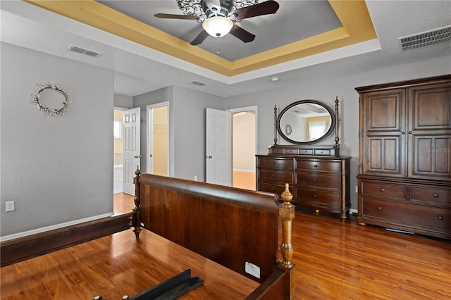 bedroom featuring ceiling fan, a raised ceiling, a walk in closet, a closet, and dark hardwood / wood-style flooring