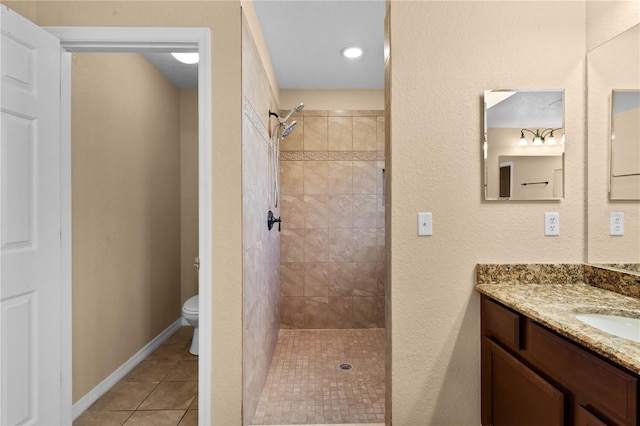 bathroom with tiled shower, vanity, toilet, and tile patterned floors