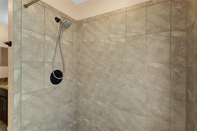 interior details featuring a tile shower and vanity