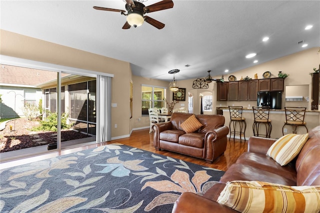 living room featuring lofted ceiling, hardwood / wood-style floors, and ceiling fan