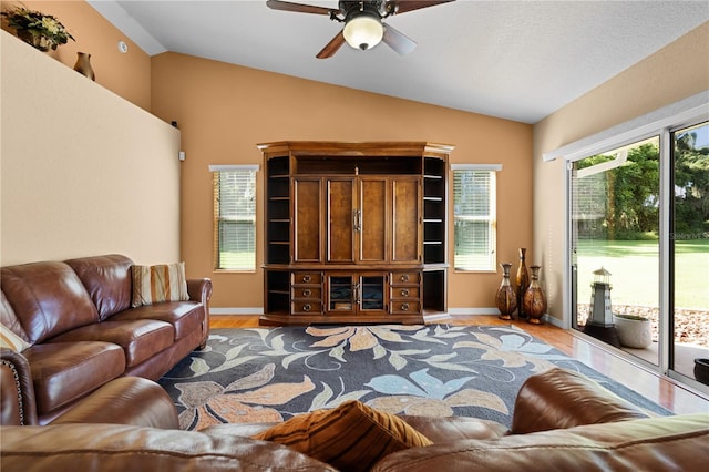 living room with ceiling fan, hardwood / wood-style floors, and vaulted ceiling