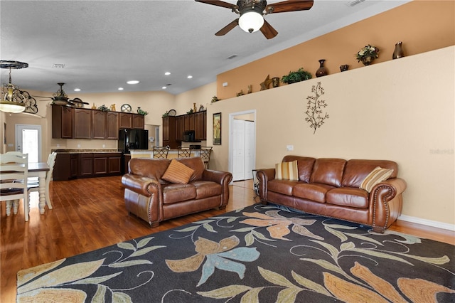 living room featuring ceiling fan, a textured ceiling, and dark wood-type flooring