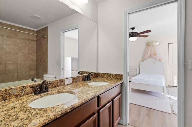 full bathroom featuring vanity, tiled shower / bath combo, a textured ceiling, hardwood / wood-style flooring, and toilet