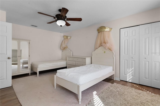 bedroom featuring a closet, ceiling fan, a textured ceiling, and dark hardwood / wood-style flooring