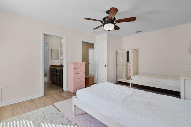 bedroom featuring ceiling fan, ensuite bathroom, and light hardwood / wood-style flooring