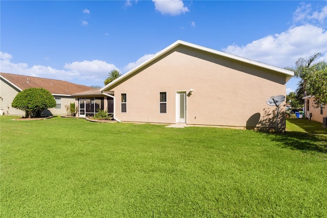 rear view of house featuring a sunroom and a yard