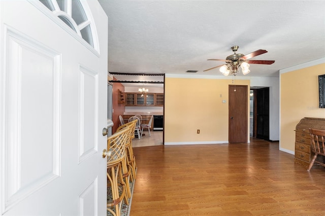 living room with ornamental molding, wood-type flooring, a textured ceiling, and ceiling fan